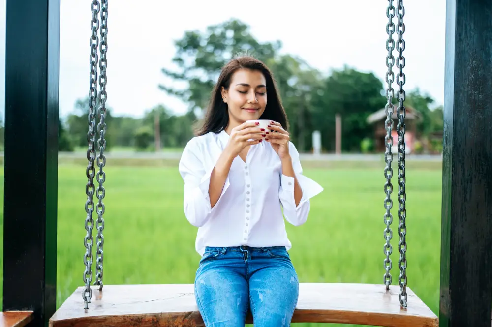 woman sitting swing holding cup coffee